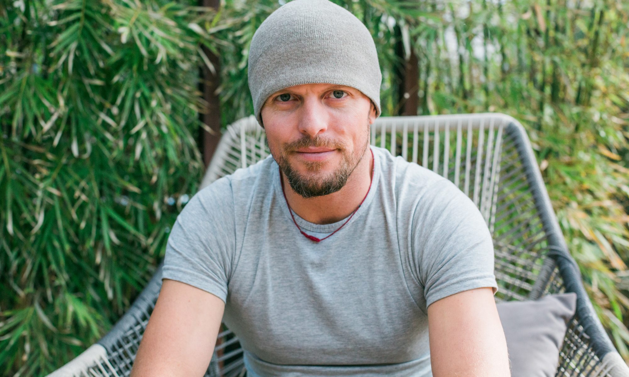 Tim Ferriss sitting in a large patio chair in front of a patch of bamboo.