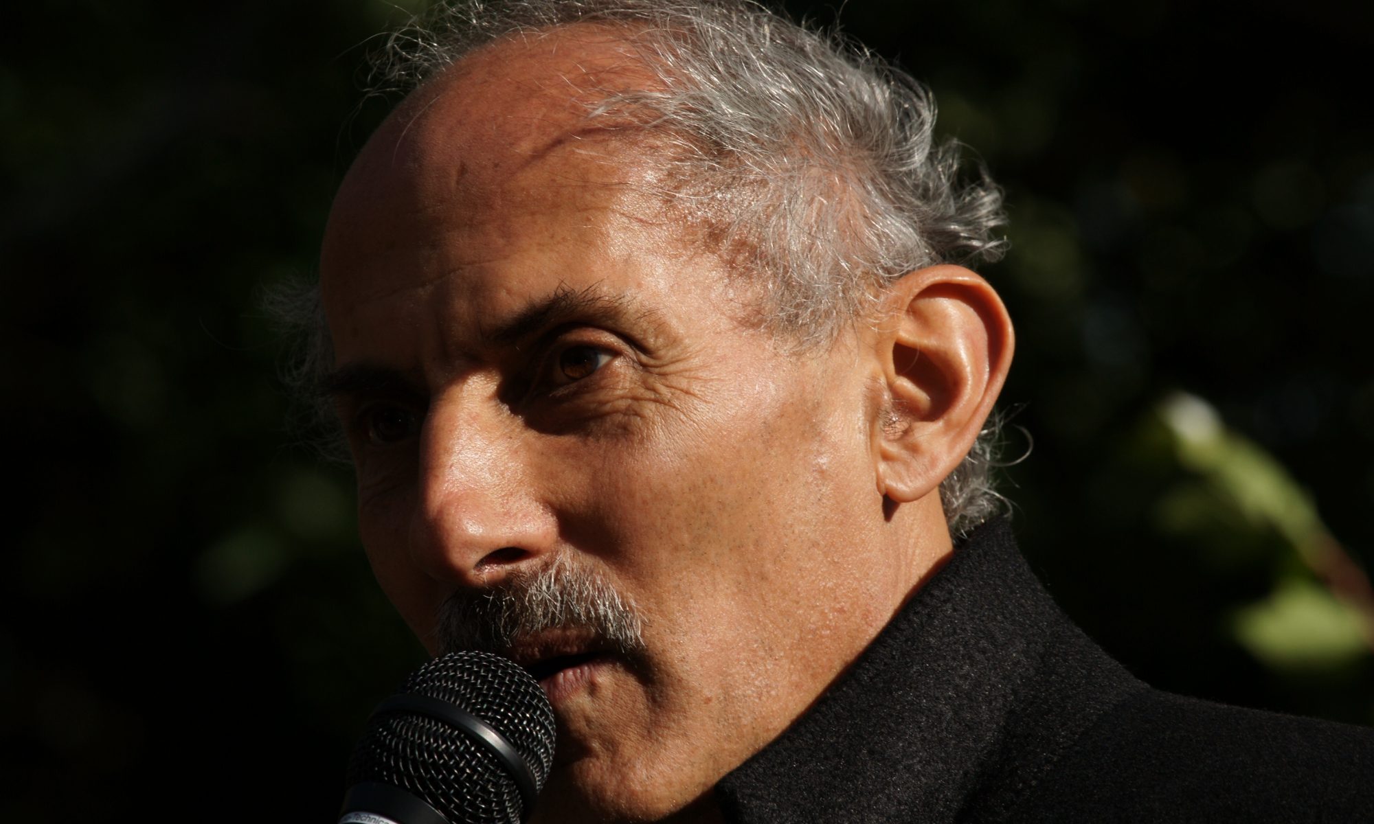 Jack Kornfield speaking at a microphone outside.