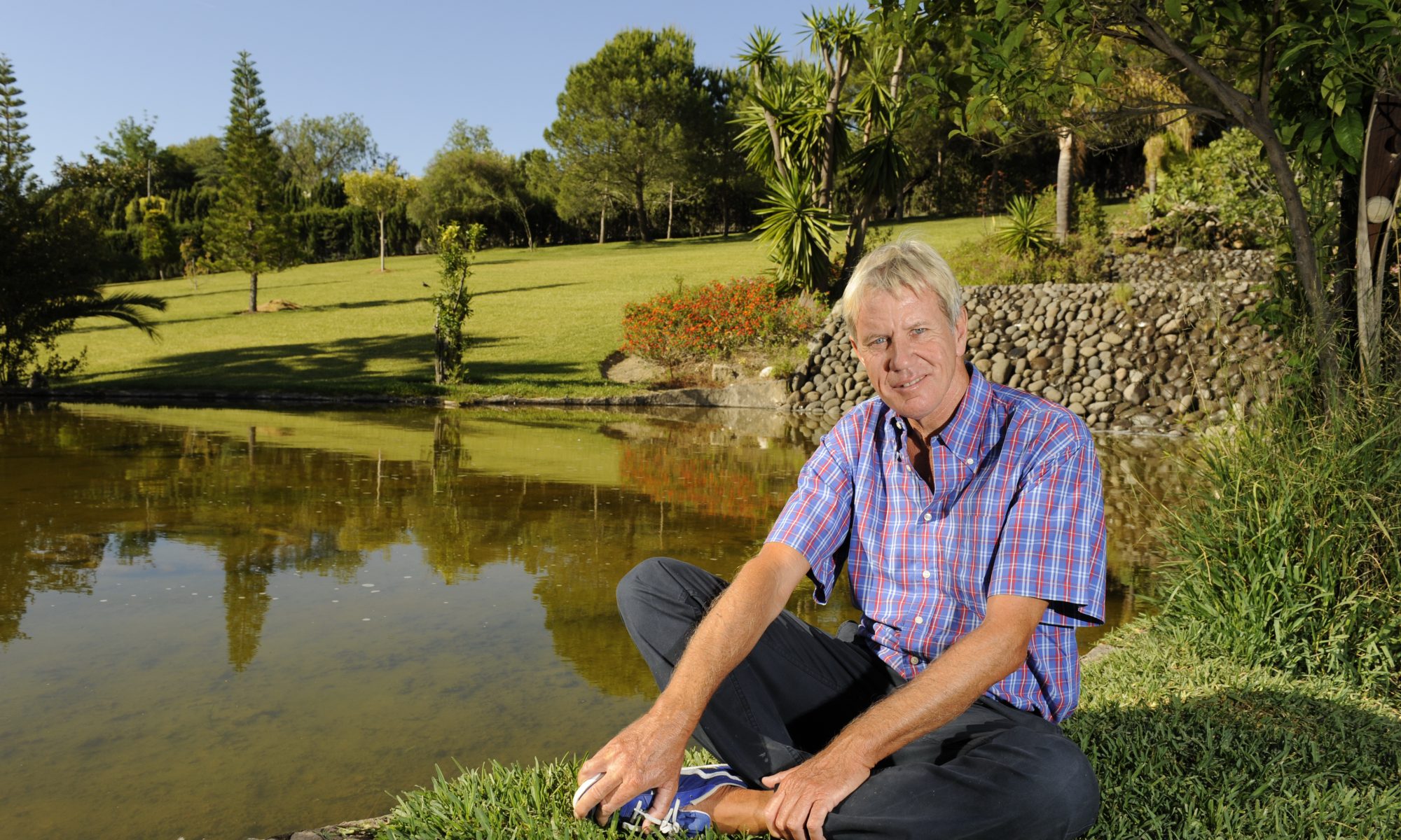 Richard Koch sitting crosslegged by a lake.
